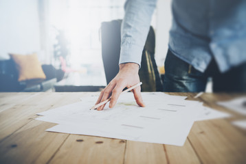 Businessman at work. Holding pencil in his hand. Architectural project on table. Blurred...