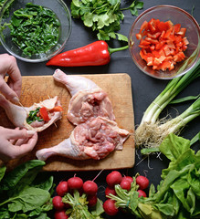 Young woman preparing chicken with vegetables