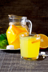The drink of fresh orange on a dark wooden table