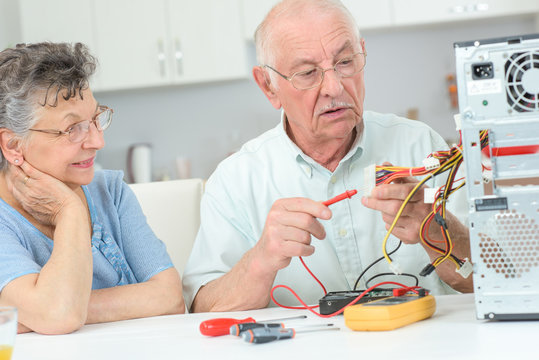 Retired man testing computer with multimeter
