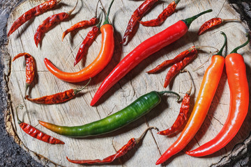 Fresh and dried chili peppers lying on a cut tree.