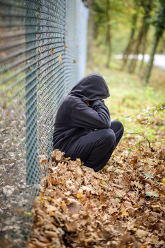 wire fence sitting in front of hooded young