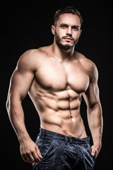 Fototapeta na wymiar attractive bodybuilder sportsman shows perfect body muscles on b