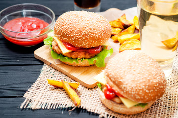 food, fast food, burgers with cheese , meat patty , lettuce, sauce , Baked potatoes and a drink , cola or beer on a wooden background