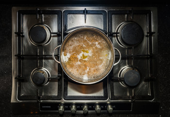 Metal cooking pan with boiling water and wholewheat penne pasta on a stove