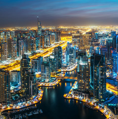 Fantastic rooftop skyline: illuminated architecture of a big city. Dubai Marina by night, United Arab Emirates.