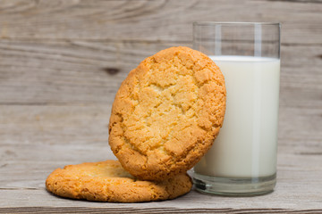 Glass of milk and huge cookies on gray wooden surface