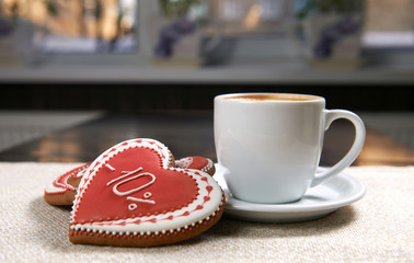 Cup of coziness. Closeup shot of red glazed Valentine’s day cookies near a cup of delicious cappuccino