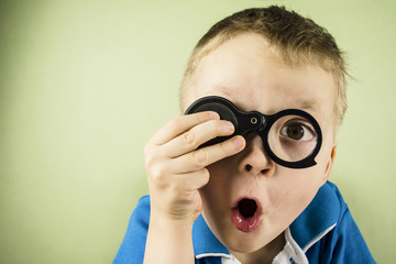 boy looking through a magnifying glass and is surprised