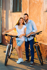 Fototapeta na wymiar Close up of young loving couple with bikes nearby wall