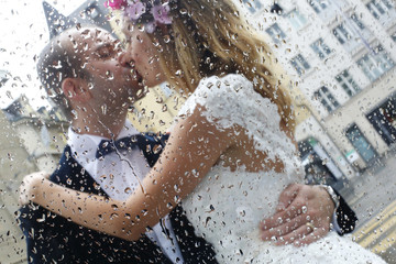 Beautiful bride and groom embracing in rain