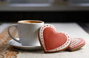 Love sweets? Closeup of a gingerbread heart shaped cookie served with a cup of warm coffee