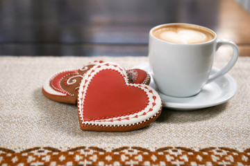 Celebrate in our cafe. High angle closeup shot of a cup of coffee decorated with froth art next to heart shaped glazed cookies