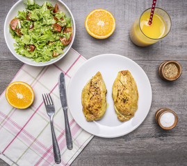 Healthy food for athletes two fried chicken breasts with curry, fresh orange juice, fresh salad on wooden rustic background top view close up