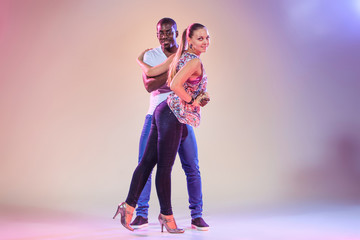 Young couple dances social Caribbean Salsa, studio shot 