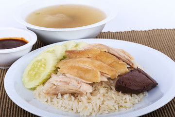 Hainanese chicken rice, steamed chicken, chicken blood and white rice on brown cloth background.