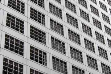 Fototapeta premium Perspective and underside angle view pattern of office building windows background.