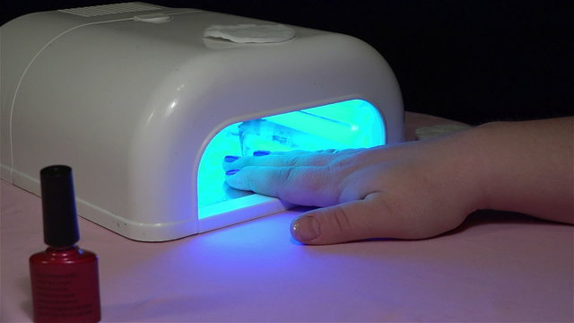 Girl dries nail in a special lamp after application to the nails
