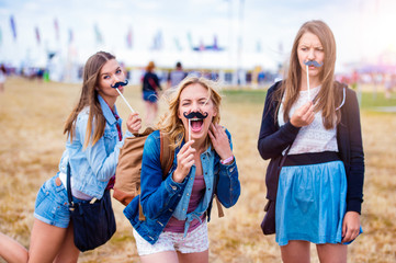 Teenage girls at summer festival with fake mustache