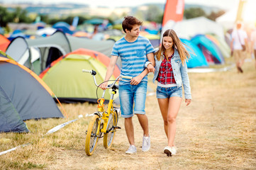 Teenage couple with yellow bike at summer music festival
