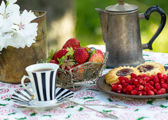 ранний завтрак в саду с чашкой кофе печеньицами и спелыми красными ягодами клубники