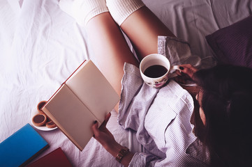 Obraz premium Girl drinking morning coffee and reading a book with copyspace