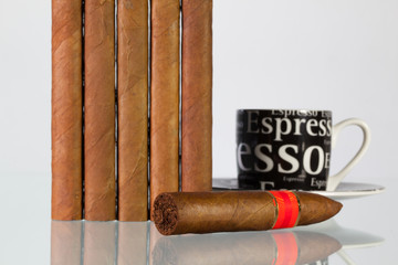 Different cigars and cup of coffee on a  glass table