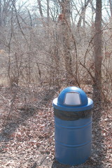 Blue trash can in woods along hiking trail