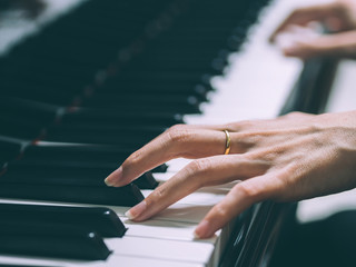 Close up of the hands of a young woman playing piano, selective