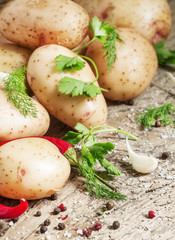 Fresh spring potatoes with spices on the old wooden background i