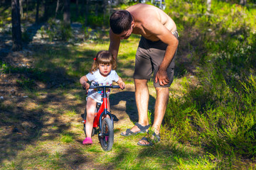 Young father helping daughter to ride  Bicycle.