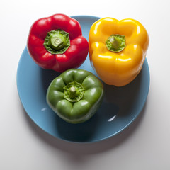 Pimientos rojo, verde y amarillo sobre plato azul
