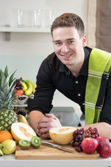 Young smiling man with a lot of fresh Fruits
