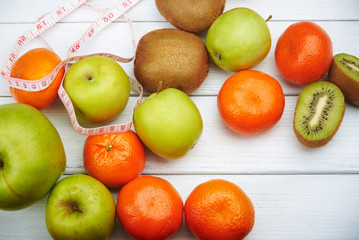Tropical fruits and apples with measuring tape,