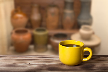 Coffee in a cup on wooden table opposite a defocused the interio