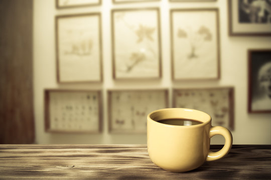 Coffee in a cup on wooden table opposite a defocused the interio