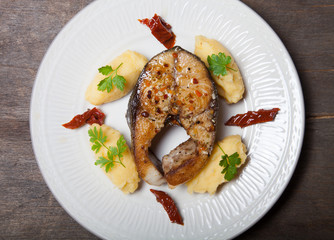 Fried tuna fish with mashed potato, dried tomato and parsley on