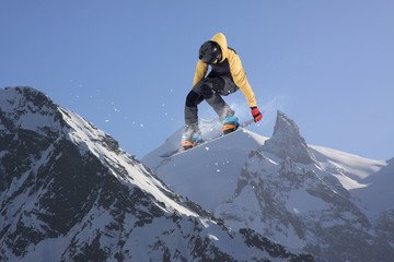 Flying snowboarder on mountains. Extreme sport.