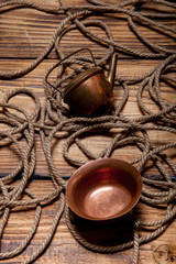 Rope and copper utensils on old wooden burned table or board for