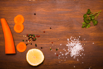 Salt, pepper and vegetables on old wood background. Toned