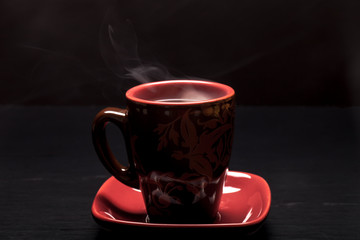 A cup of coffee with smoke on black background