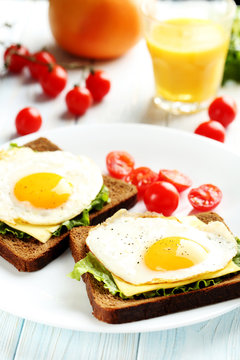 Fried eggs with toasts on plate on blue wooden table