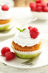 Raspberry cupcakes on plate on white wooden background