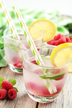 Raspberries and juice in glass on grey wooden background