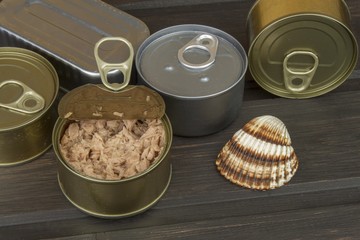 Tuna cans on a dark wooden table. Sales of canned fish. Diet food. Fishing industry.
