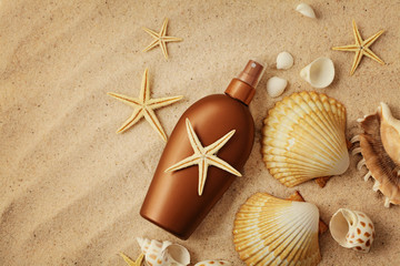 suntan lotion and seashells on sand