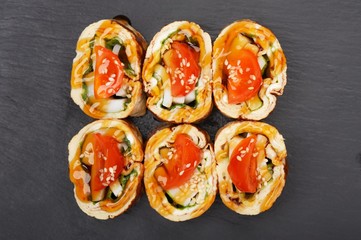 Set of tasty japanese rolls with omelette and tomatoes on black