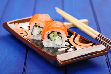 Pair of japanese rolls with salmon and cucumber on flat plate wi