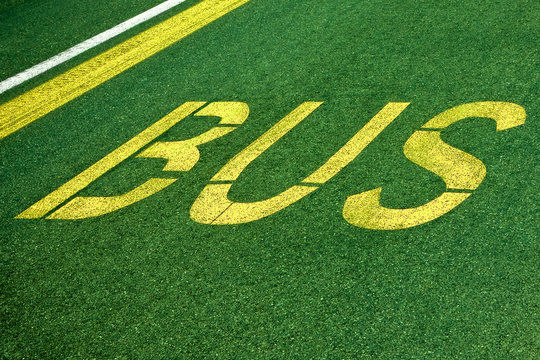 Bus written on green asphalt - Travel by bus, concept image