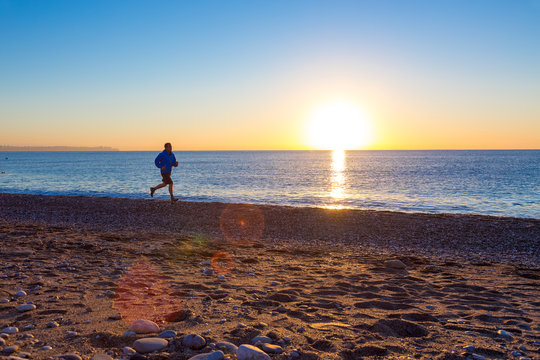 Silhouette of male Jogger on Ocean Beach at Sunrise